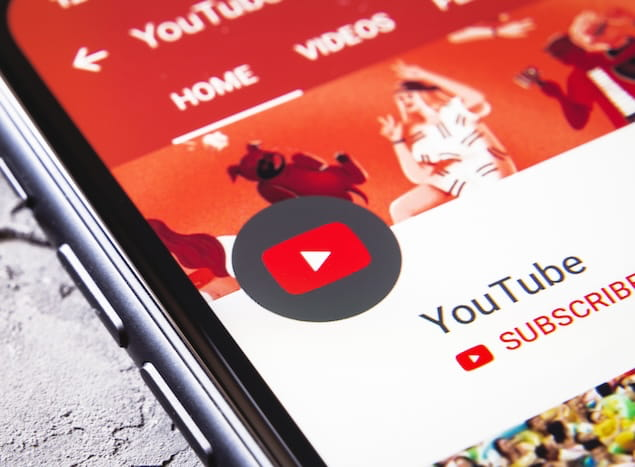 Close-up of a smartphone screen showing the YouTube app home tab with the subscribe button visible